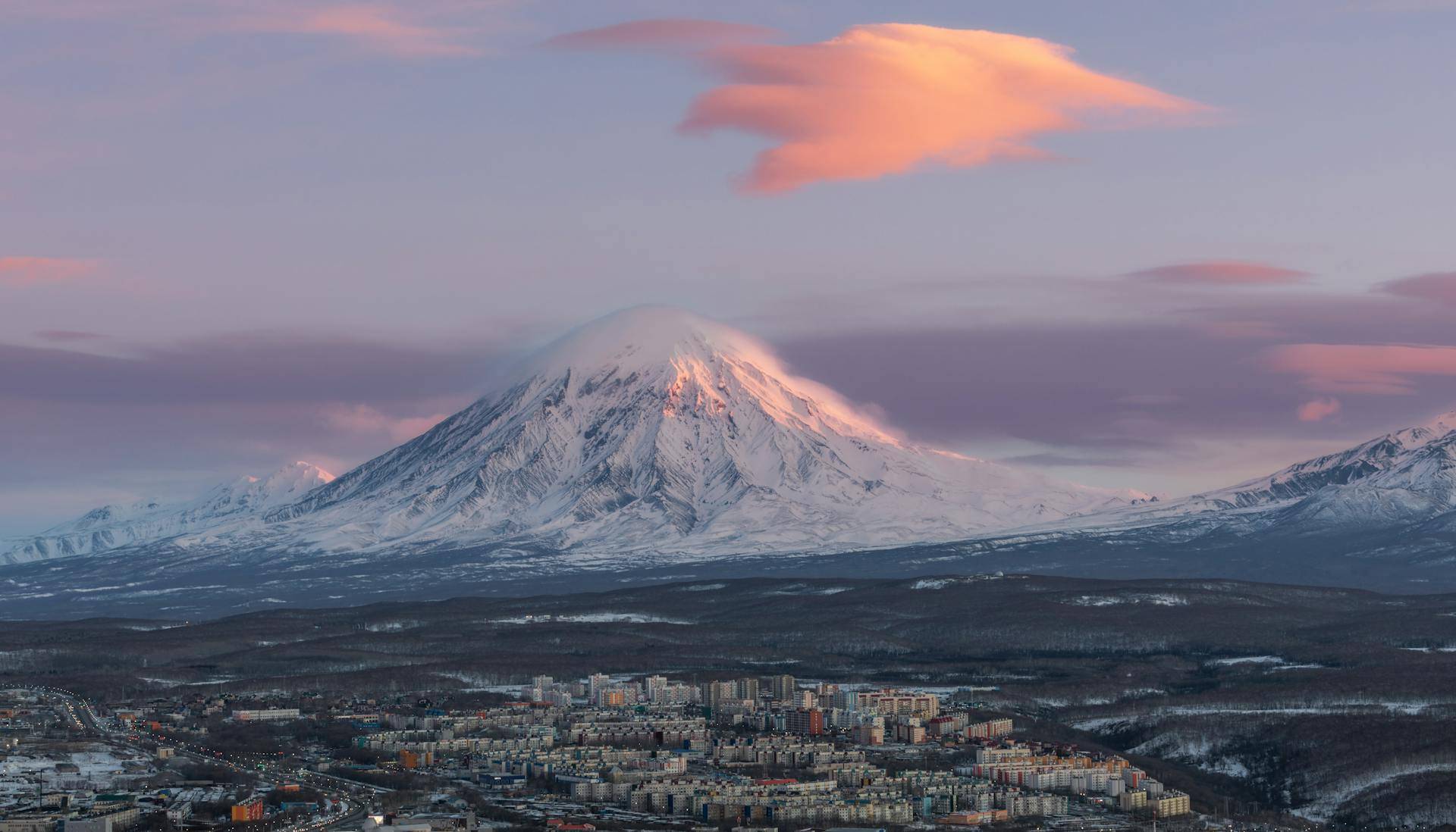 Aerial view of Petropavlovsk-Kamchatsky: tiny houses below and a snow-covered mountain in the distance